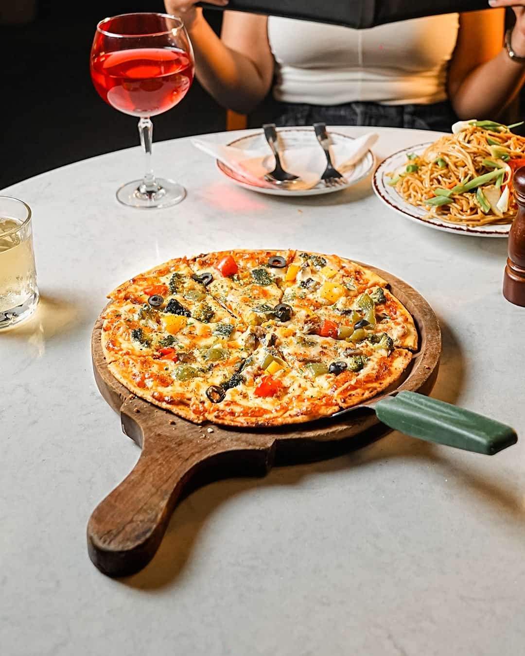 Wood-fired pizza on a wooden board at Azure, Panchkula